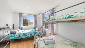 Une chambre de dortoir avec des lits superposés, un bureau et une fenêtre avec des rideaux.