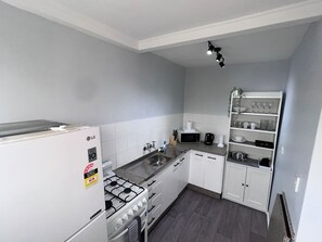 A compact kitchen with white cabinets, a gas stove, a microwave, and a sink. - u2-Cute Fresh Unit|Quiet Centre|NewAC|SmartTV (Norman Park)