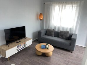 A modern living room with a flat-screen TV, a grey sofa, a wooden coffee table, and a floor lamp. - u2-Cute Fresh Unit|Quiet Centre|NewAC|SmartTV (Norman Park)