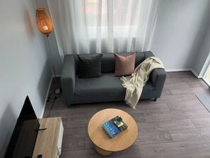 Una sala de estar moderna con un sofá gris, una mesa de centro redonda y una lámpara de pie.