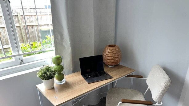 Een werkplek met een laptop, een stoel, een plant en een decoratieve vaas.