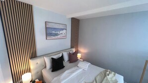 Een hotelkamer met een bed, nachtkastjes, een lamp en een schilderij aan de muur.