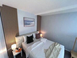 A hotel room with a bed, bedside tables, a lamp, and a painting on the wall. - u2-Cute Fresh Unit|Quiet Centre|NewAC|SmartTV (Norman Park)