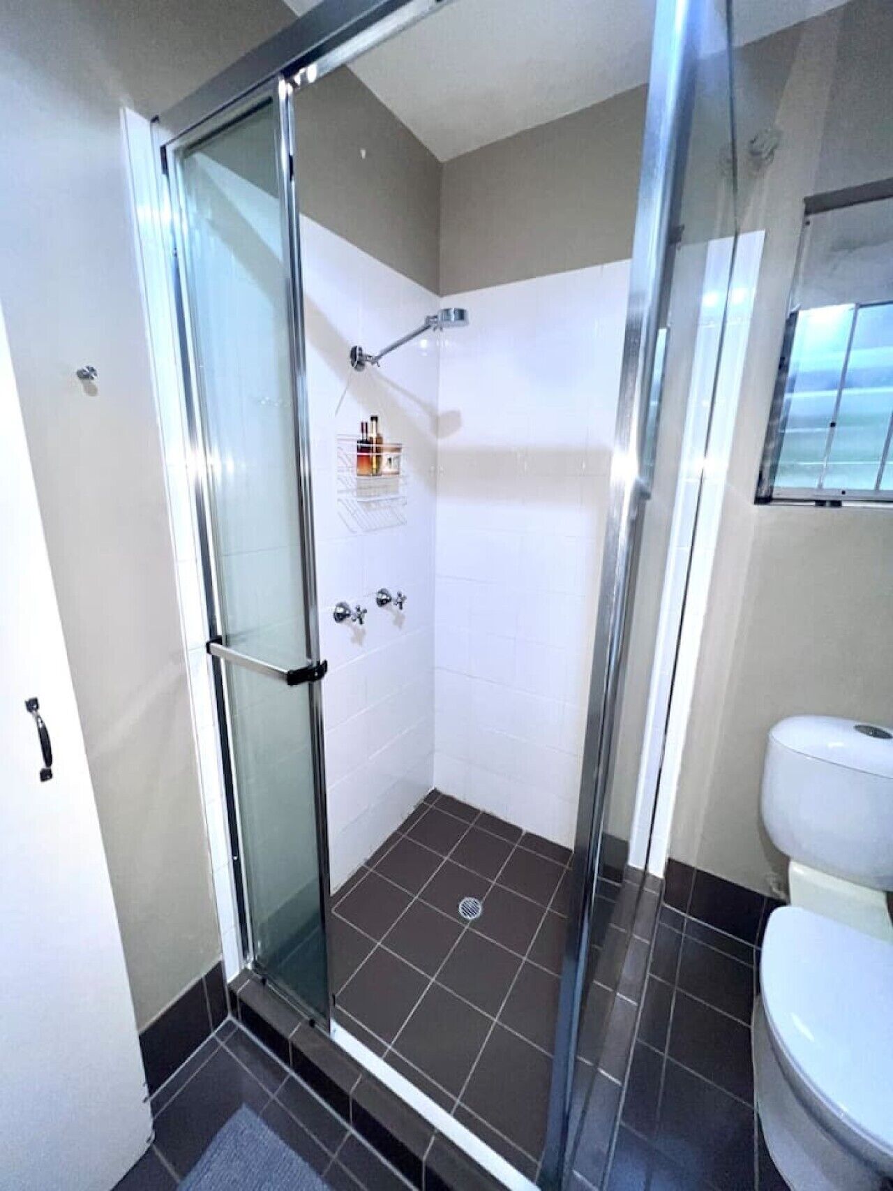 Ein modernes Badezimmer mit einer gläsernen Duschkabine, einer Toilette und einem gefliesten Boden.