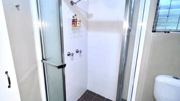 Une salle de bain moderne avec une douche à parois de verre, des toilettes et un sol carrelé.