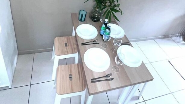 A dining area with a wooden table set for four, a clock on the wall, and a potted plant. - u4-Traditional Unit-Quiet Close CBD-AirConSmartTV (Norman Park)