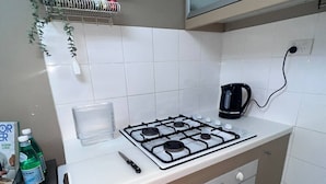 A kitchen with a gas stove, a kettle, and a coffee maker. - u4-Traditional Unit-Quiet Close CBD-AirConSmartTV (Norman Park)