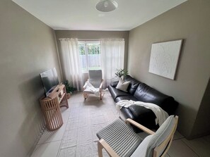 Una sala de estar con televisor, sofá, sillón y mesa.