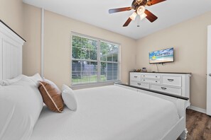 A bedroom with a bed, a dresser, a television, and a ceiling fan. - Coastal Orange Beach Retreat | Minutes to the Beach, The Wharf & Family Fun (Orange Beach)