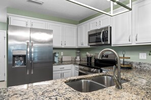 A modern kitchen with stainless steel appliances, granite countertops, and white cabinetry. - Coastal Orange Beach Retreat | Minutes to the Beach, The Wharf & Family Fun (Orange Beach)