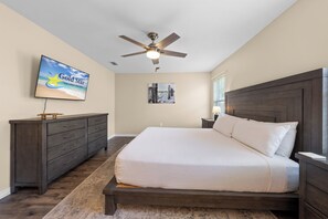 A bedroom with a bed, a dresser, a ceiling fan, a TV, and a wall-mounted picture. - Coastal Orange Beach Retreat | Minutes to the Beach, The Wharf & Family Fun (Orange Beach)