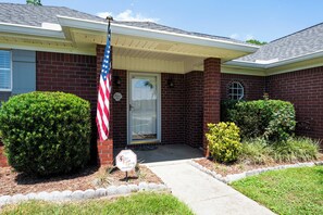 A residential building with a brick facade, a front door, and a small porch area. - Coastal Orange Beach Retreat | Minutes to the Beach, The Wharf & Family Fun (Orange Beach)