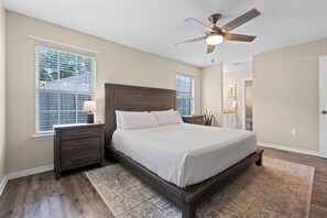 A bedroom with a bed, nightstands, a ceiling fan, and a window with blinds. - Coastal Orange Beach Retreat | Minutes to the Beach, The Wharf & Family Fun (Orange Beach)