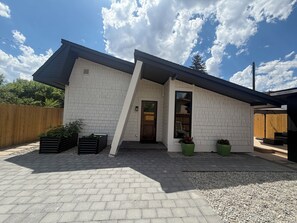 A modern house with a sloped roof, a brick exterior, and a front porch with potted plants.