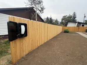 A fenced backyard with a wooden fence, a gravel path, and a house in the background.