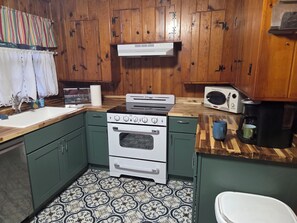 A kitchen with wooden cabinets, a stove, a microwave, and a coffee maker.