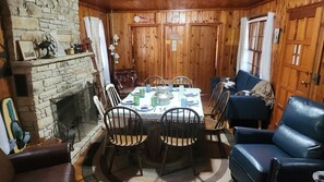 Un comedor acogedor con chimenea, paredes de madera y un sofá de cuero azul.