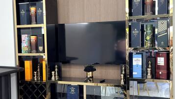 A modern living room with a large flat-screen TV, black and gold entertainment center, and a plush black sofa.