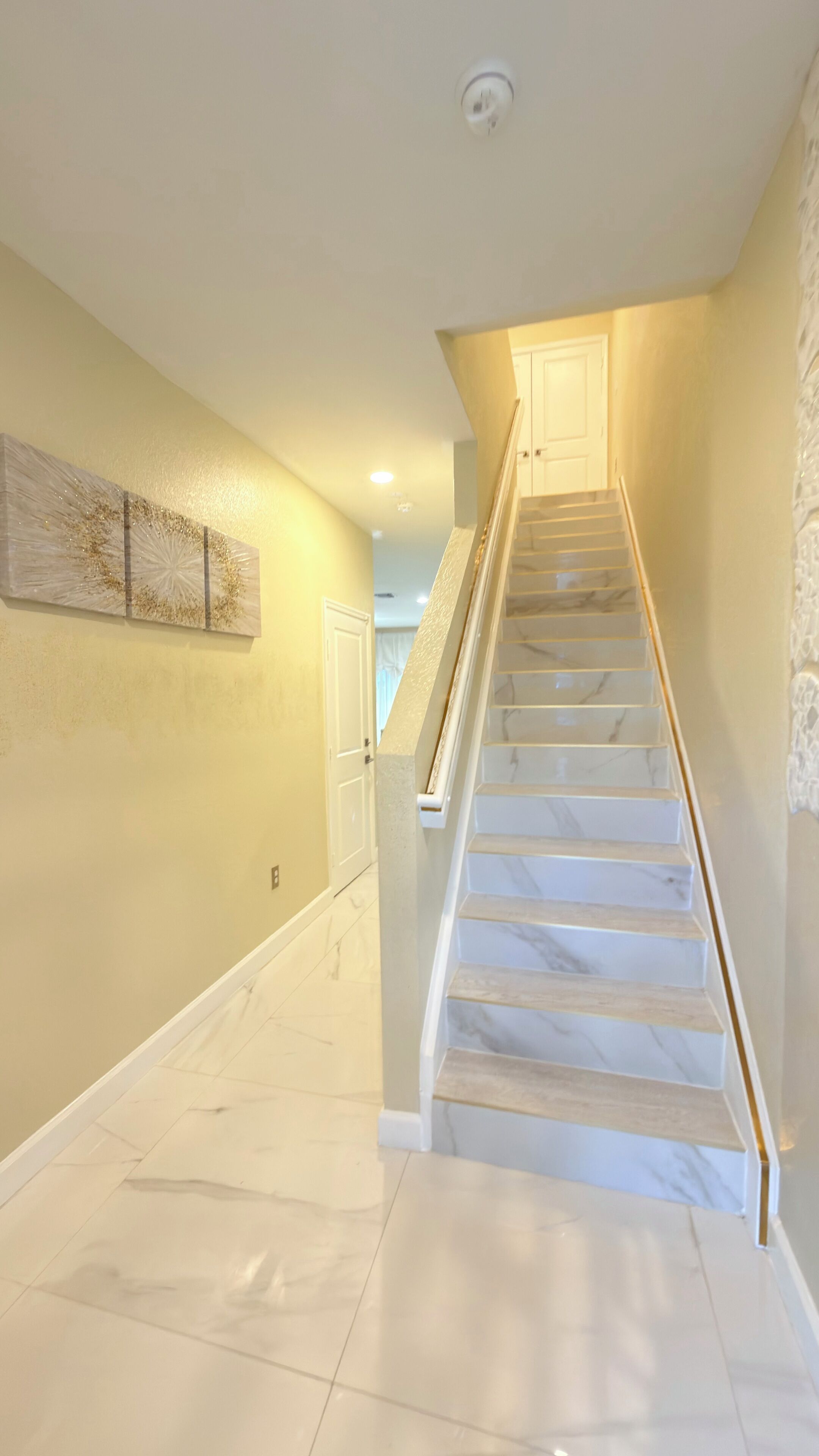 A staircase with marble steps and a handrail, leading to a door at the top.