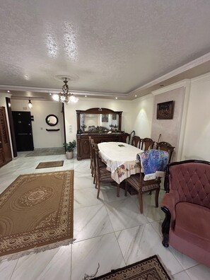Un coin repas avec une table dressée pour quatre personnes, entourée de chaises, d’un lustre et d’un miroir placé au-dessus de la table.