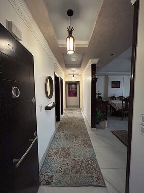 A hallway with patterned tiles, a black door, and a hanging light fixture. - Luxury 3 bedroom Apartment in Rehab October City (Giza Governorate)