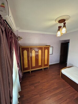 Une pièce avec une armoire en bois, un lit et un luminaire fixé au plafond.