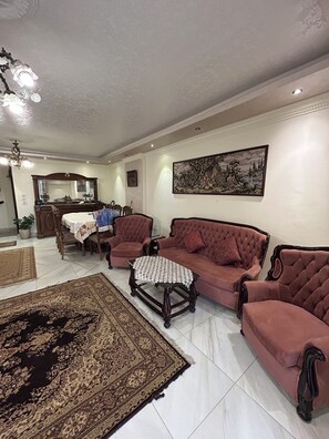 A living room with a sofa set, a coffee table, a rug, and a painting on the wall. - Luxury 3 bedroom Apartment in Rehab October City (Giza Governorate)