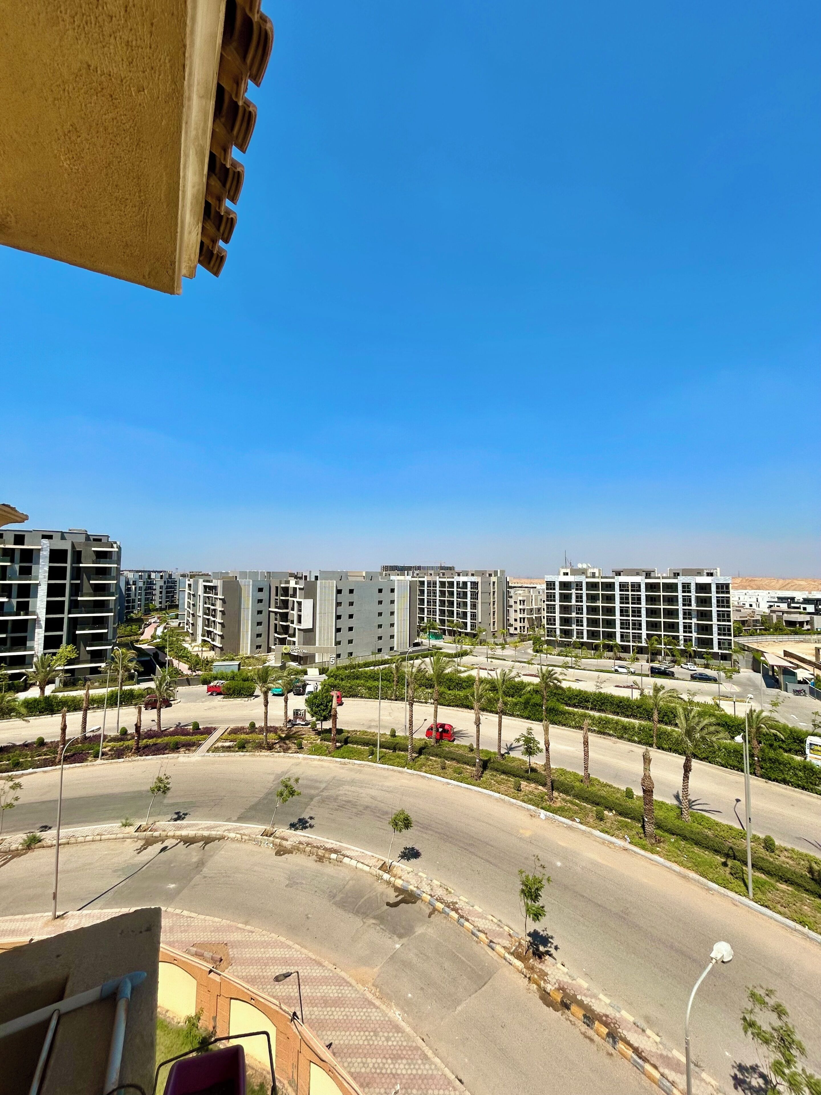 Zona residencial con edificios modernos, una calle curva y palmeras.