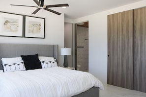 Un dormitorio con cama, ventilador de techo, mesita de noche, lámpara y armario.