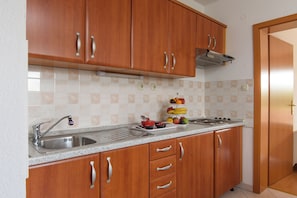 A kitchen with wooden cabinets, a stainless steel sink, and a fruit display. - A 1  apt w shared pool and balcony, near the beach (Seget Vranjica)