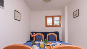 A dining area with a table set for breakfast, including bread, eggs, and a vase of flowers. - A 1  apt w shared pool and balcony, near the beach (Seget Vranjica)