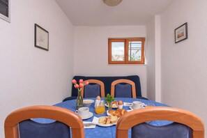 A dining area with a table set for breakfast, including bread, eggs, and a vase of flowers. - A 1  apt w shared pool and balcony, near the beach (Seget Vranjica)