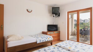 A bedroom with two beds, a television, and a sliding glass door leading to an outdoor area. - A 1  apt w shared pool and balcony, near the beach (Seget Vranjica)
