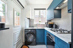 A compact kitchen with a washing machine, a sink, and a stove. - Emerald Garden Suite - Wifi,Parking,Garden,Sleep 2 (London)