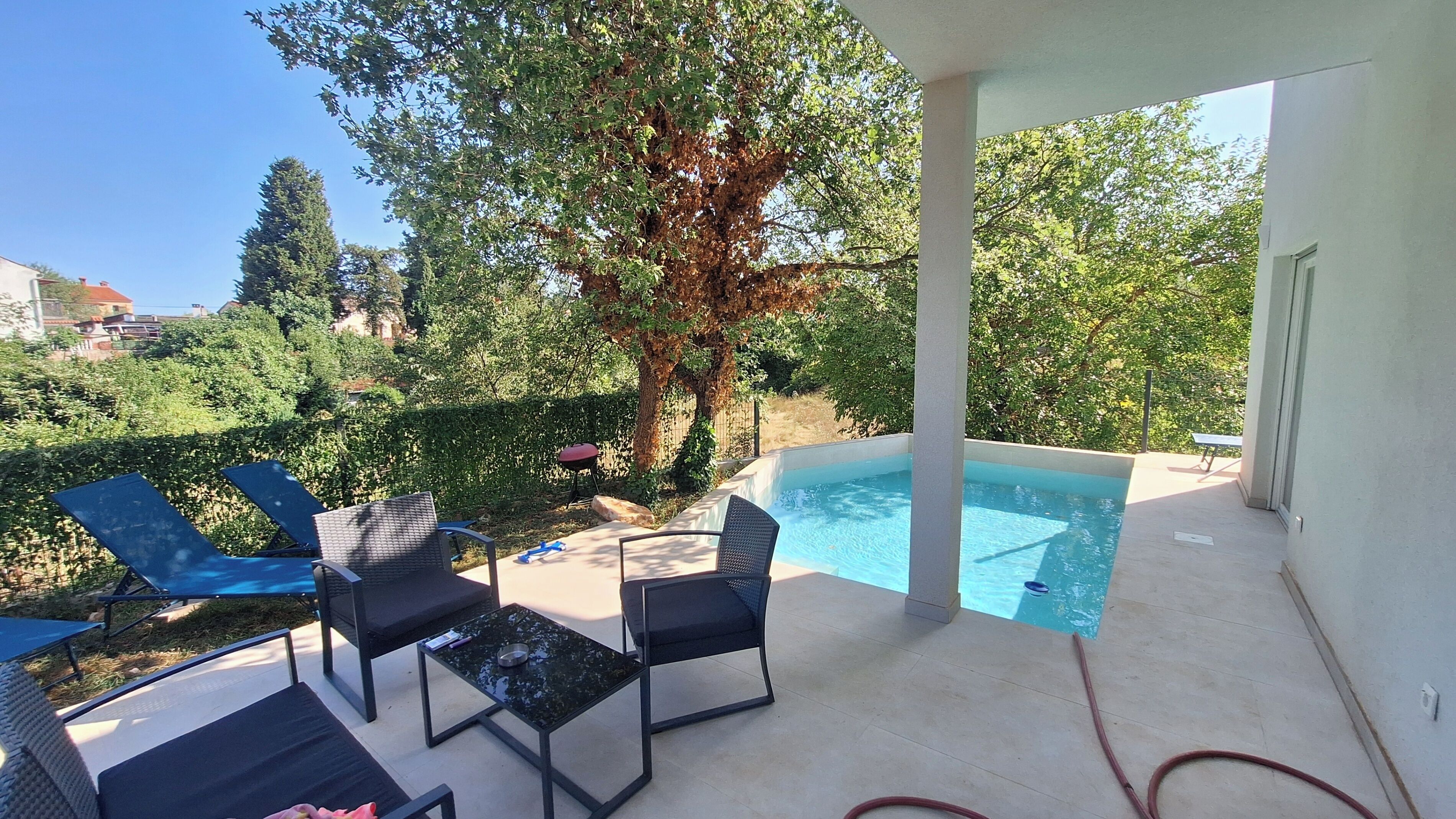 A poolside area with lounge chairs, a table, and a clear view of the pool.