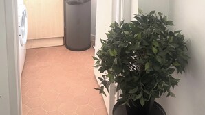 A hallway leading to a kitchen with a trash bin and a potted plant. - Cozy London Apartment with City Views (London)