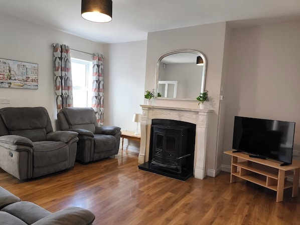 A living room with a fireplace, a television, and two leather sofas.