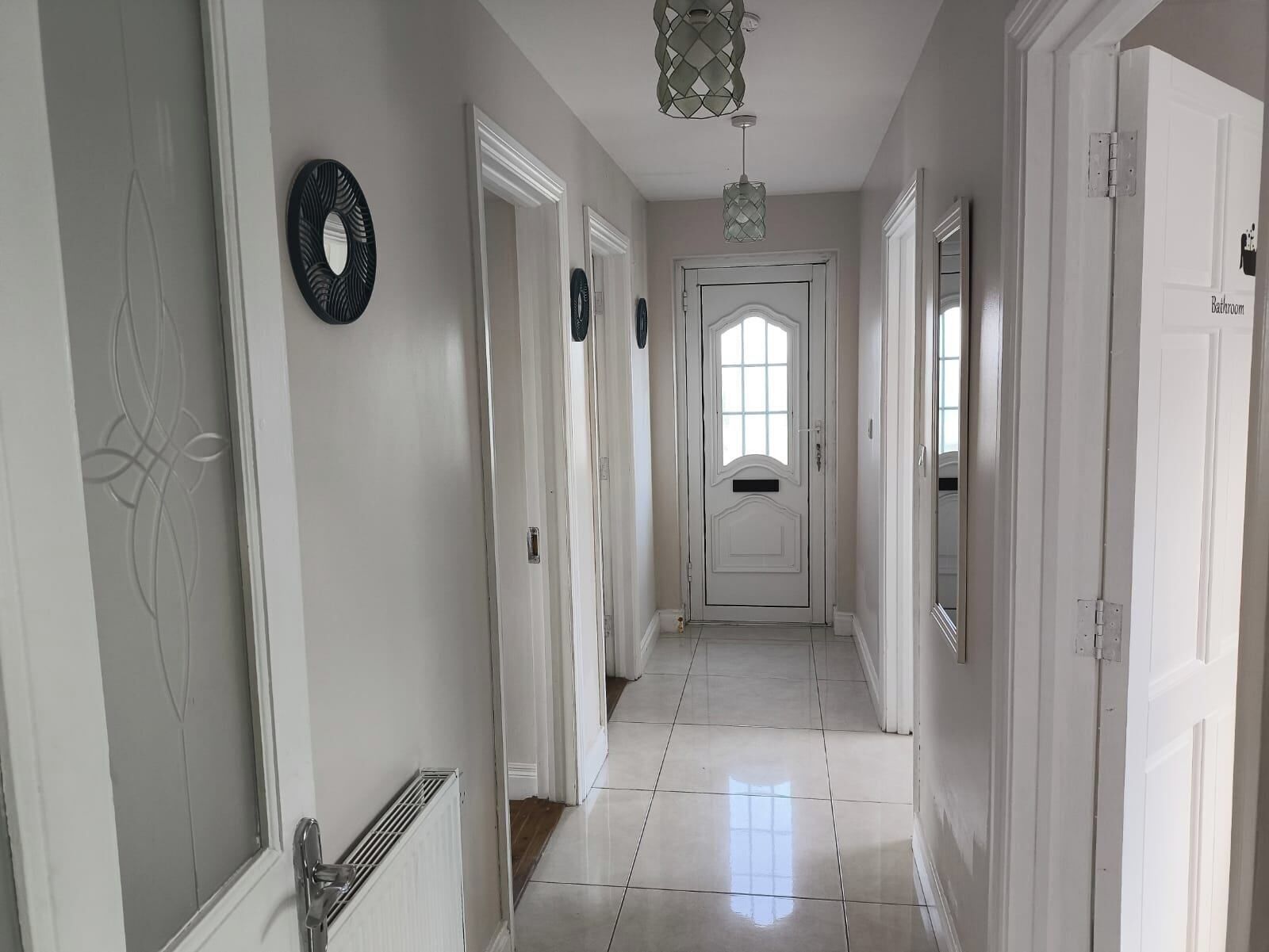 A hallway with white doors, a radiator, and a light fixture.