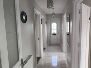 A hallway with white doors, a radiator, and a light fixture.