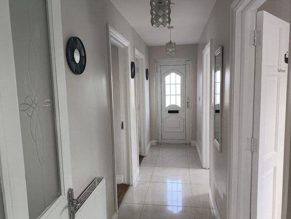 A hallway with white doors, a radiator, and a light fixture.
