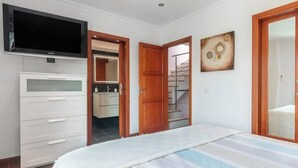 A bedroom with a bed, a TV, a wardrobe, and a door leading to a bathroom. - Casa Encanto Arinaga (Aguimes)
