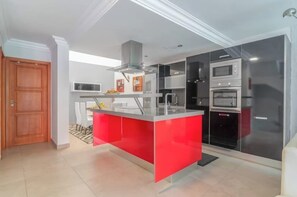 Uma cozinha moderna com ilha central, eletrodomésticos embutidos e área de jantar com cadeiras.