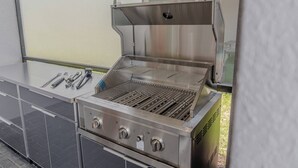 Un barbecue d’extérieur en acier inoxydable, doté d’une grille plate, d’un couvercle et d’un panneau de commande avec des boutons.
