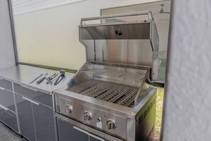 A stainless steel outdoor grill with a flat grate, a hood, and a control panel with knobs. - Go!#37 - WINDSOR ISLAND (Davenport)