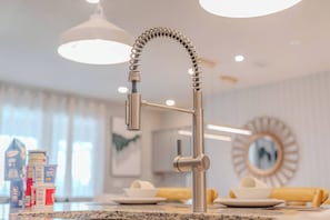 Eine moderne Küche mit einem Edelstahlarmaturen, einer Arbeitsplatte aus Granit und einem runden Spiegel an der Wand.