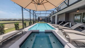 Un espace piscine comprenant un jacuzzi, des chaises longues et un patio couvert.