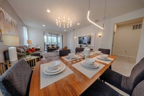 A modern dining area with a wooden table set for four, surrounded by patterned chairs. - Go!#41 - WINDSOR AT WESTSIDE (Kissimmee)