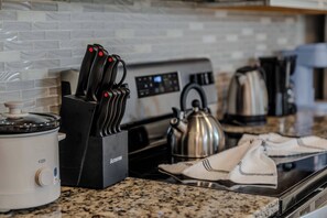 A kitchen with a stove, a kettle, a coffee maker, and a knife block. - Go!#41 - WINDSOR AT WESTSIDE (Kissimmee)