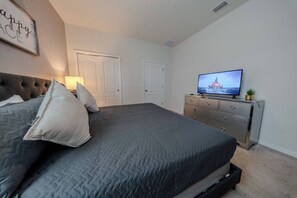 A bedroom with a bed, a dresser, a television, and a door. - Go!#41 - WINDSOR AT WESTSIDE (Kissimmee)