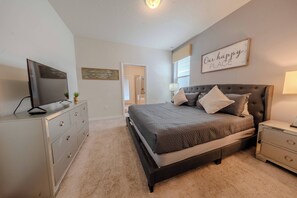 A bedroom with a bed, a dresser, a television, and a wall sign. - Go!#41 - WINDSOR AT WESTSIDE (Kissimmee)